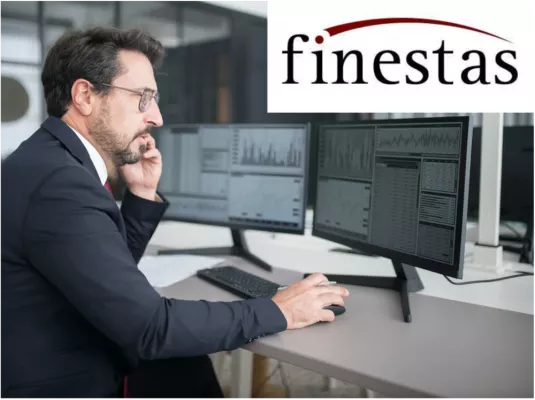 Ein Mann arbeitet konzentriert vor zwei Bildschirmen mit Börsenkursen. 